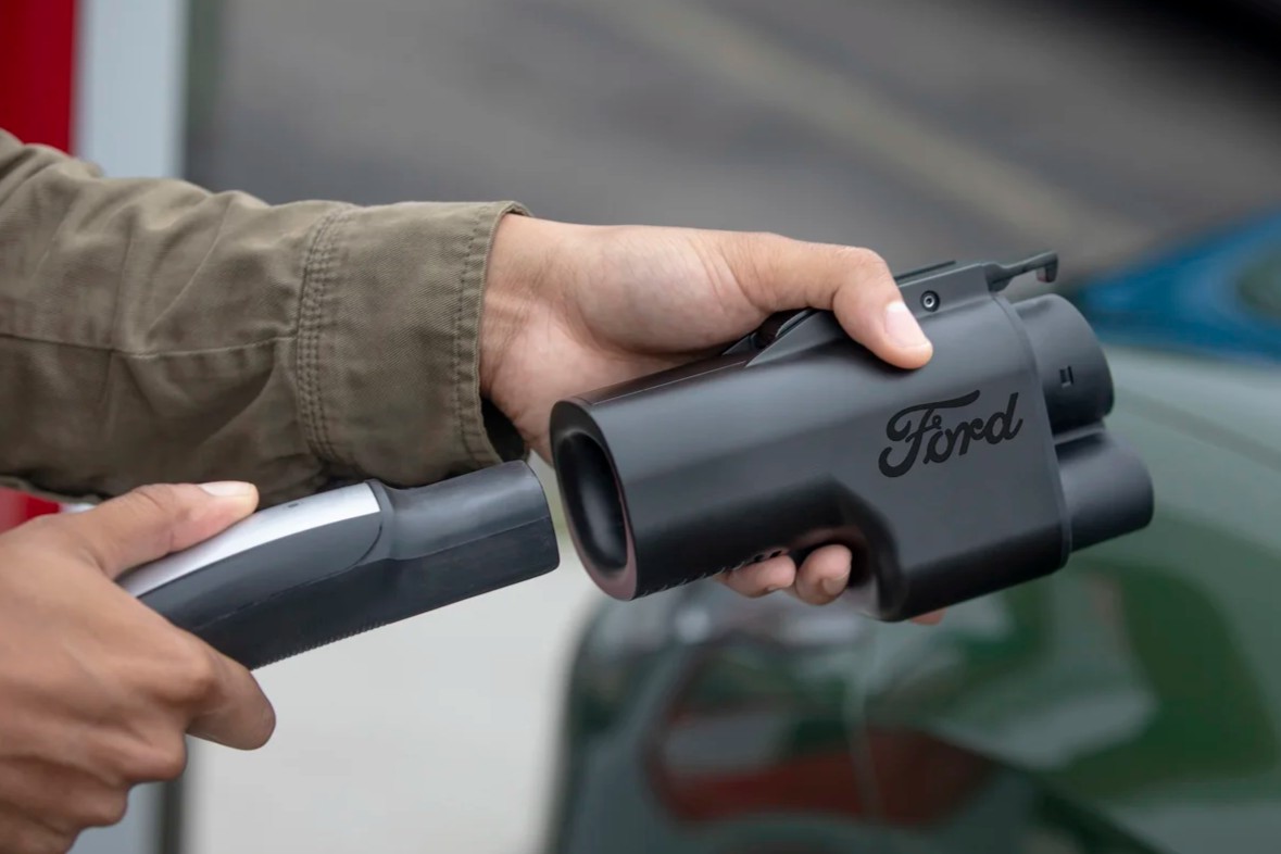 A photo of a Tesla Supercharger being plugged into a Ford power adapter.