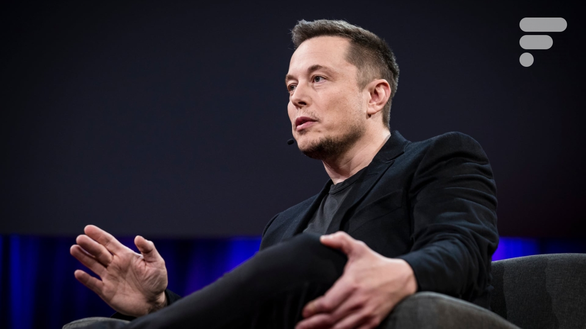 Une photo en contre-plongée d'Elon Musk assis sur un fauteuil avec un fond noir derrière