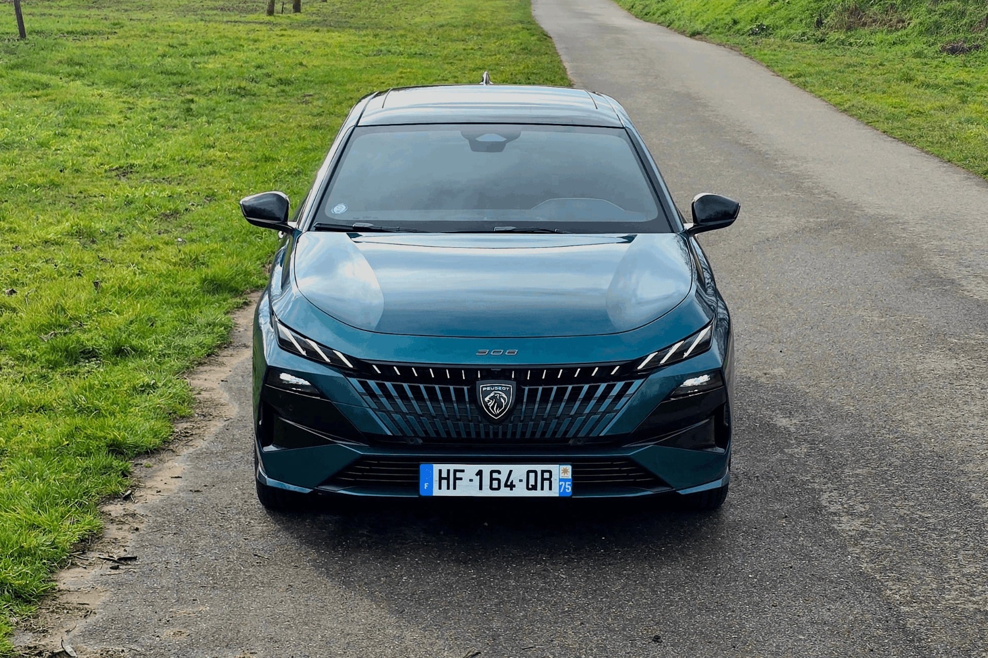 Vue de face de la nouvelle Peugeot 308 électrique 2026 grise avec son nouveau logo rétroéclairé et sa signature lumineuse à LED.