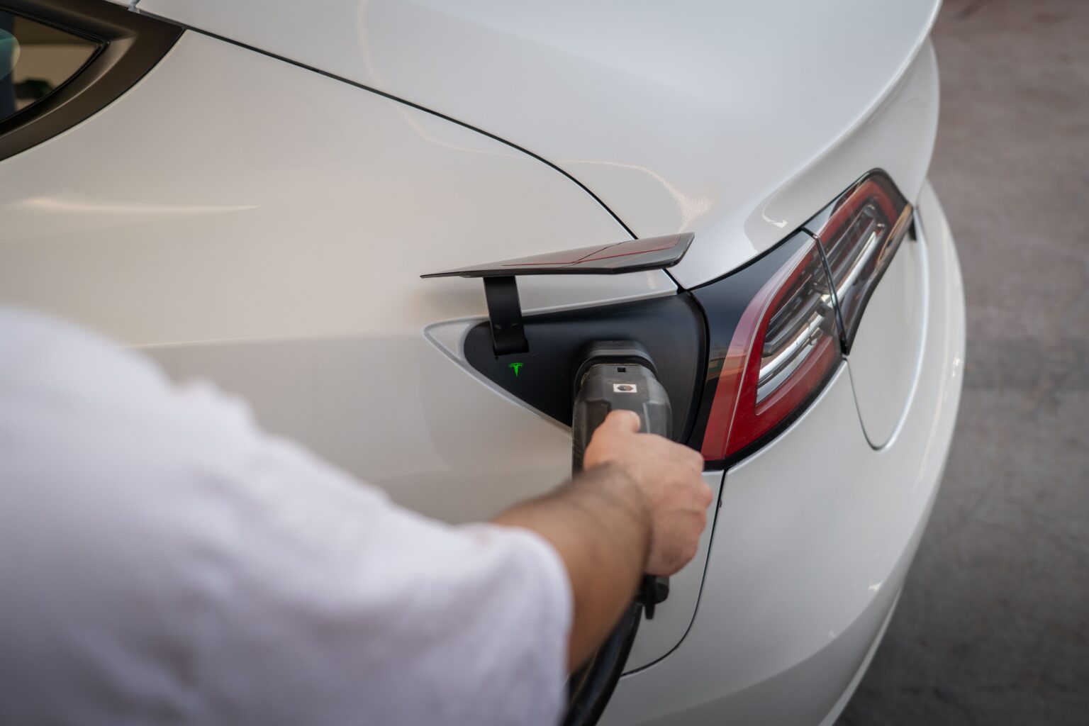 Conducteur branchant le câble de recharge sur une voiture électrique à domicile