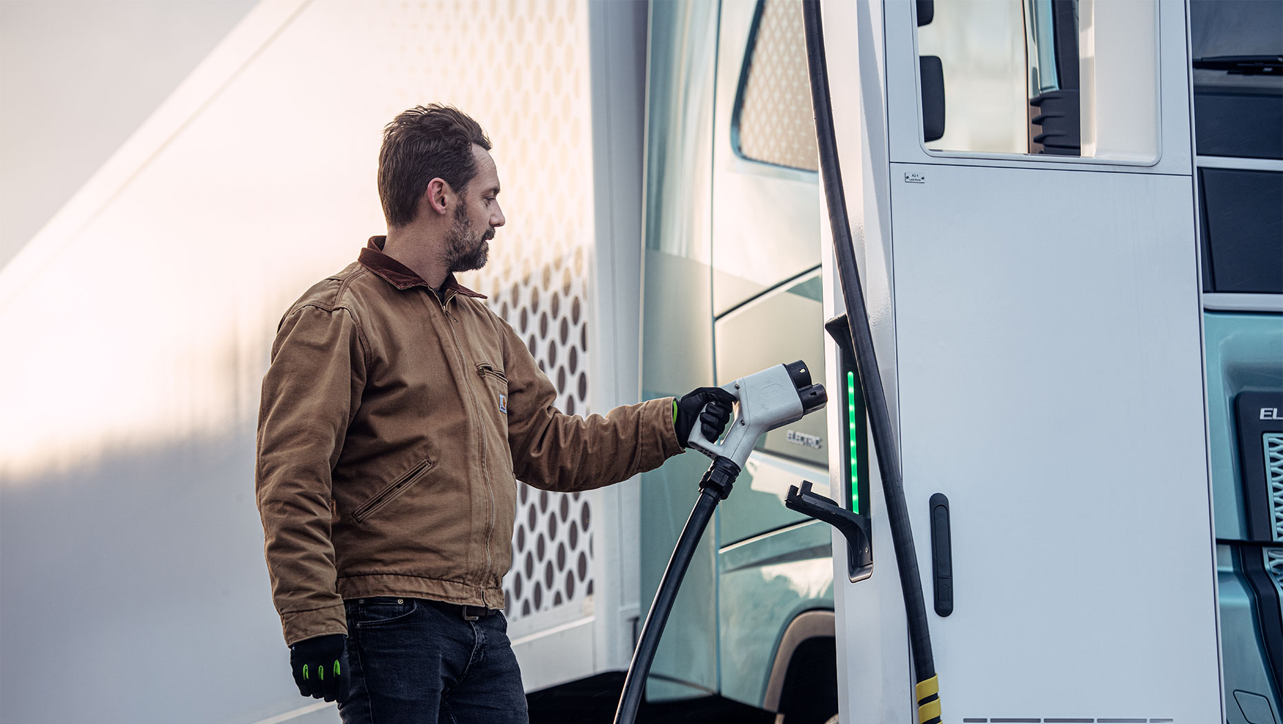 Homme rechargeant un poids lourd électrique